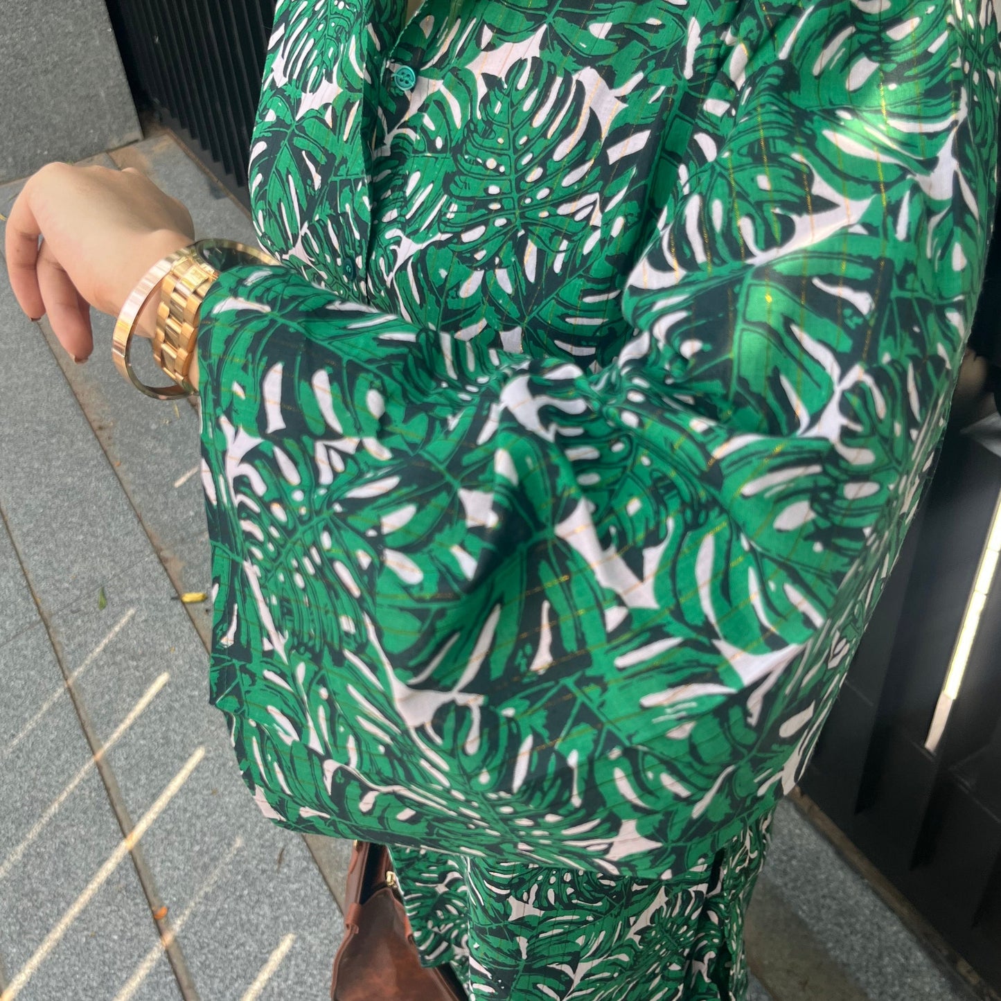 Person wearing a green and white patterned dress bending over on a tiled floor.